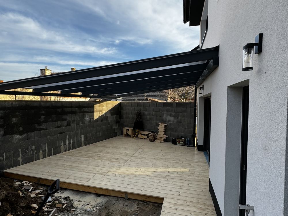 Zastřešená terasa s dřevěnou podlahou u bílého domu