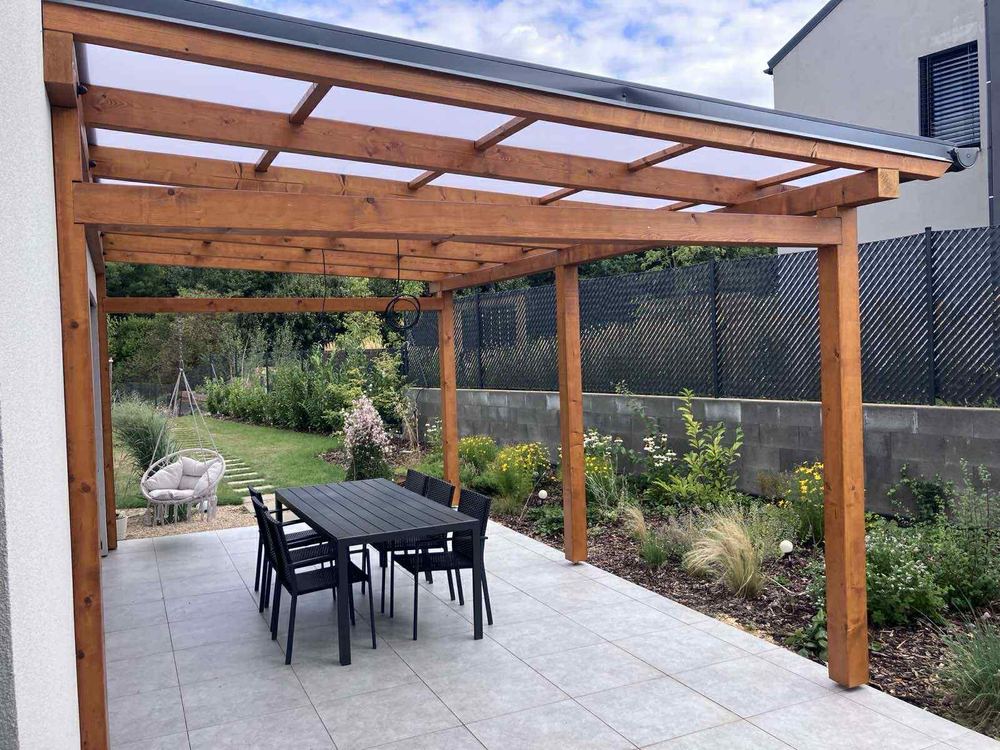Pergola s proskleným zastřešením nad dlážděnou terasou