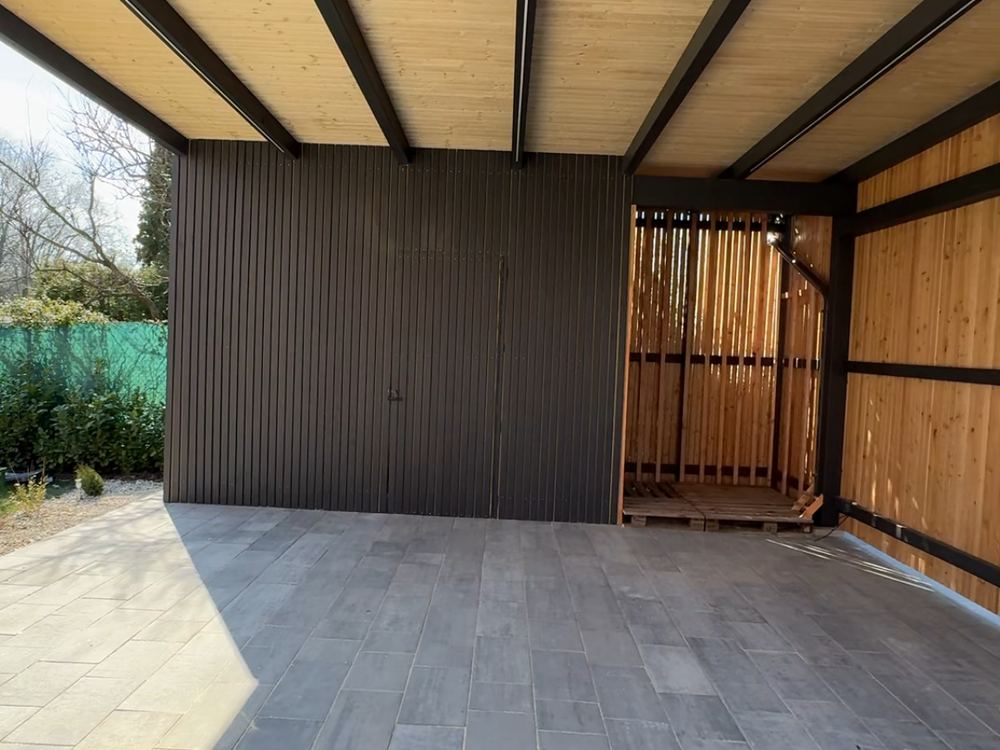 Vnitřek carportu s dřevěným obkladem a posuvnou brankou